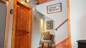A wooden door, a chair, a framed picture, and a staircase. - Aviator Cabin (Talkeetna)