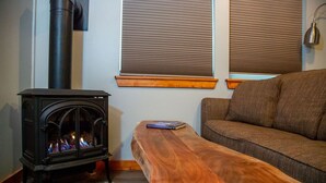 A cozy living room with a wood-burning stove, a wooden bench, and a sofa. - Aviator Cabin (Talkeetna)
