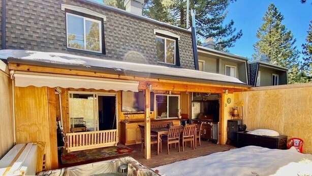 Een huis met een hottub, een houten terras en een overdekte patio.
