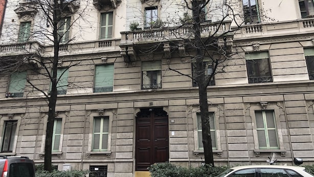 A building with a large central door, multiple windows with shutters, and a tree in front. - House Giussano, elegant two-room apartment in the center (Milano)