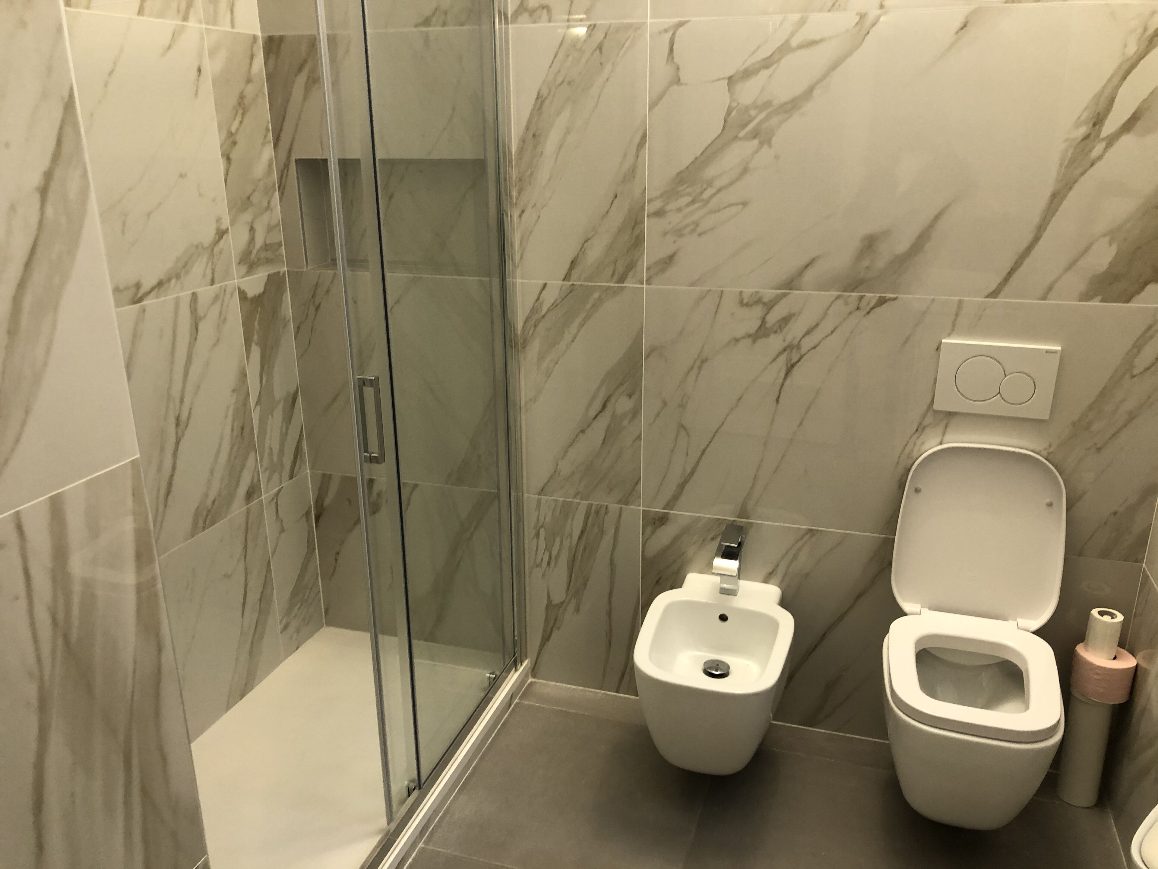 Un baño moderno con cabina de ducha de cristal, un bidé y un inodoro.