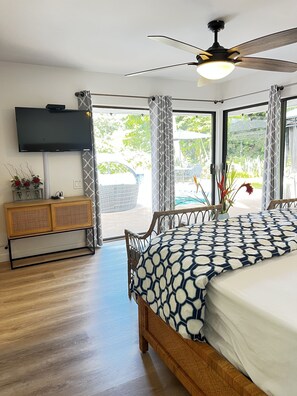 A bedroom with a bed, a TV, a ceiling fan, and a view of the outdoors. - Kona Keauhou Newly Remodeled Home, Quiet private home on Golf course with
Pool. (Kailua-Kona)