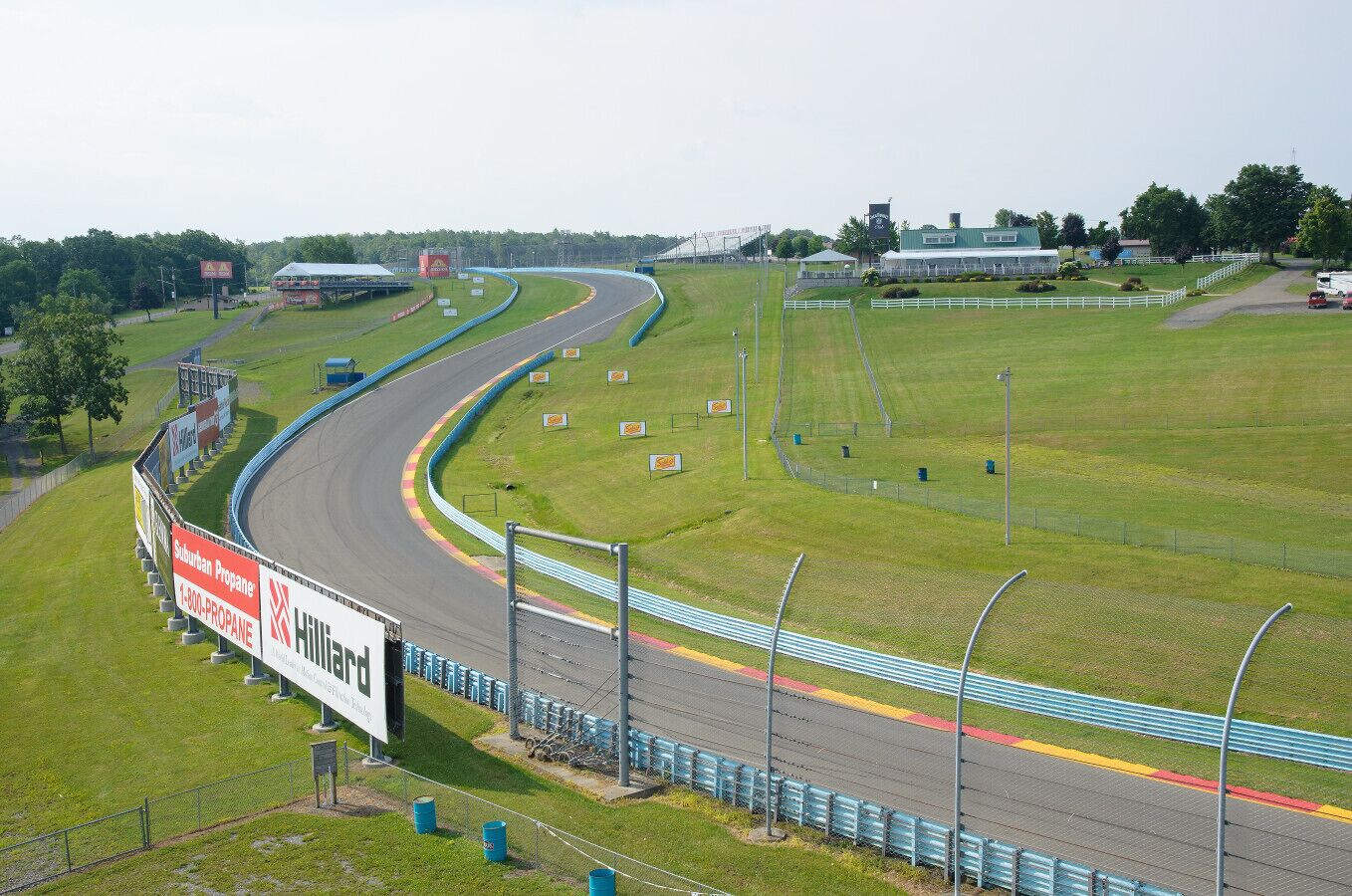 Une piste de course avec une zone herbeuse, des barrières et un bâtiment en arrière-plan.