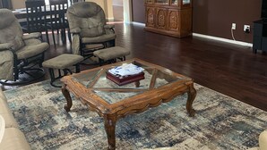Un salon avec une table basse en verre, des canapés en cuir, un meuble en bois et un lustre.