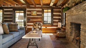 A log cabin interior with a sofa, armchair, fireplace, and rustic decor. - The Kingfisher: Flat Mountain Farm (Highlands)