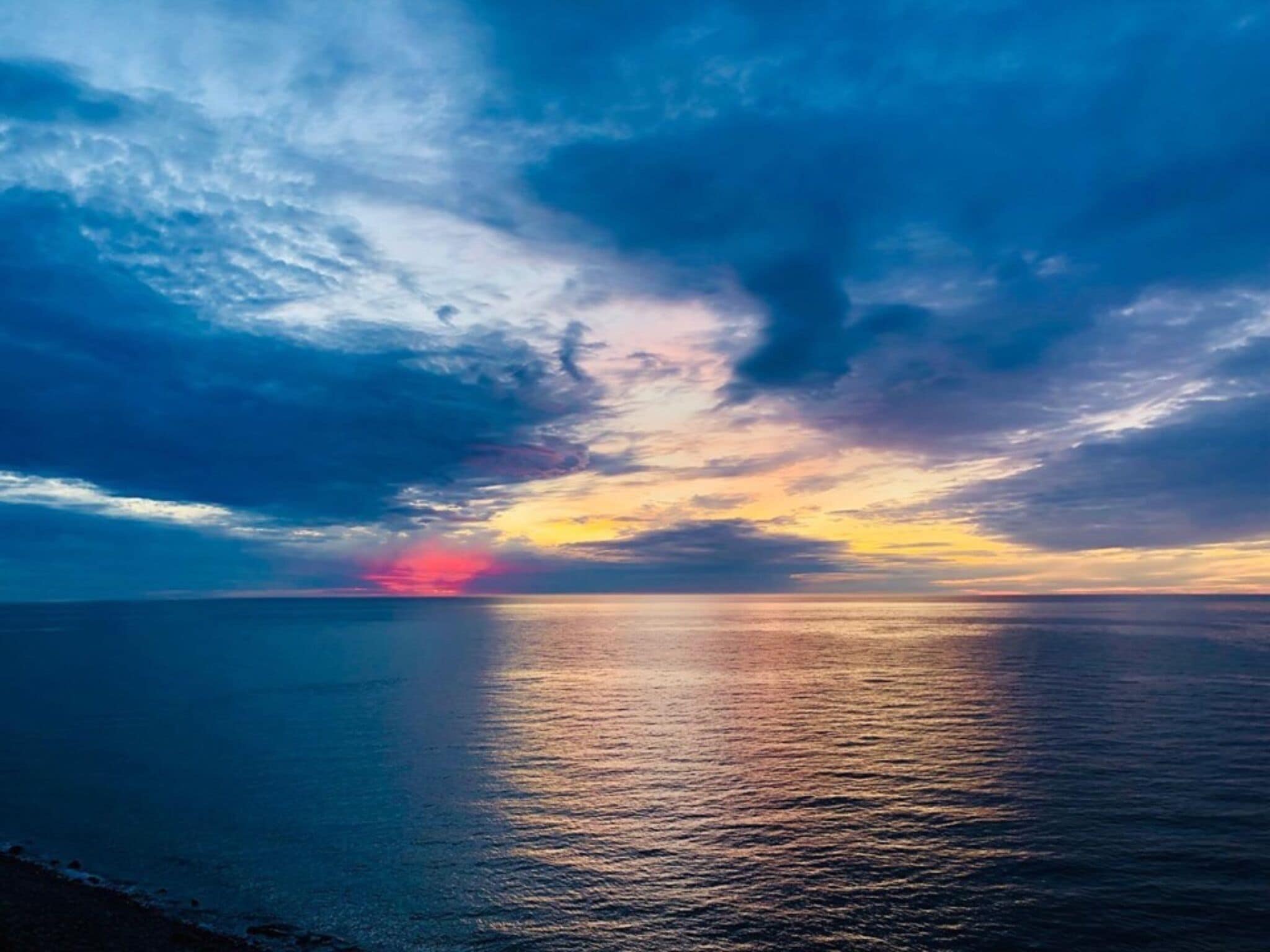 Ein Sonnenuntergang über einem ruhigen Meer mit klarem Horizont.