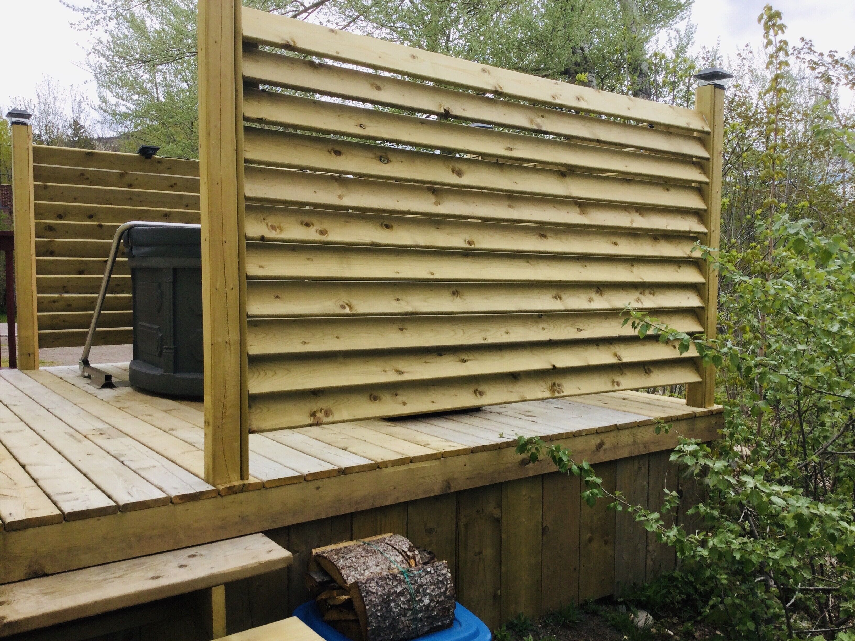Eine Holzterrasse mit Whirlpool und Sitzbank.