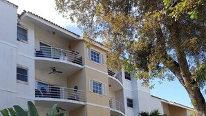 Un edificio a più piani con balconi, immerso nel verde e tra piante fiorite.