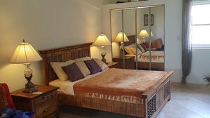 Una camera da letto con un letto, due comodini con lampade, una sedia rossa, uno specchio grande e una ventola a soffitto.