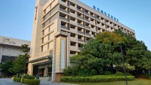 A multi-story hotel with a modern architectural design, featuring a prominent entrance and a well-maintained garden area. - Century City Badminton Club Hotel (Dongguan)