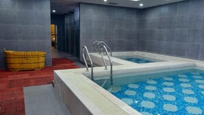 A modern indoor pool with clear blue tiles, metal ladders, and a yellow bucket. - Century City Badminton Club Hotel (Dongguan)