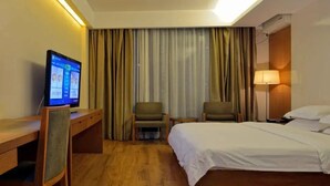 A hotel room with a bed, two chairs, a desk with a computer, and a TV. - Century City Badminton Club Hotel (Dongguan)