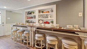 Una cucina con angolo bar, sgabelli e scaffali con oggetti decorativi.
