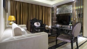 A modern living room with a sofa, a black armchair, a dining table, and a TV. - Huangcheng Imperial Garden Hotel (Hefei)