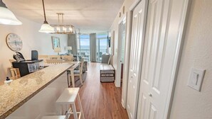 A modern kitchen with a long counter, white bar stools, and a view to the living area. - Beachfront condo with pools & hot tub (Myrtle Beach)