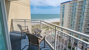 A balcony with a view of the ocean and a high-rise building. - Beachfront condo with pools & hot tub (Myrtle Beach)