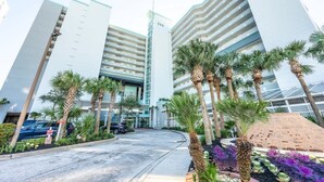 A modern hotel with a central atrium, multiple floors, and palm trees in the foreground. - Beachfront condo with pools & hot tub (Myrtle Beach)