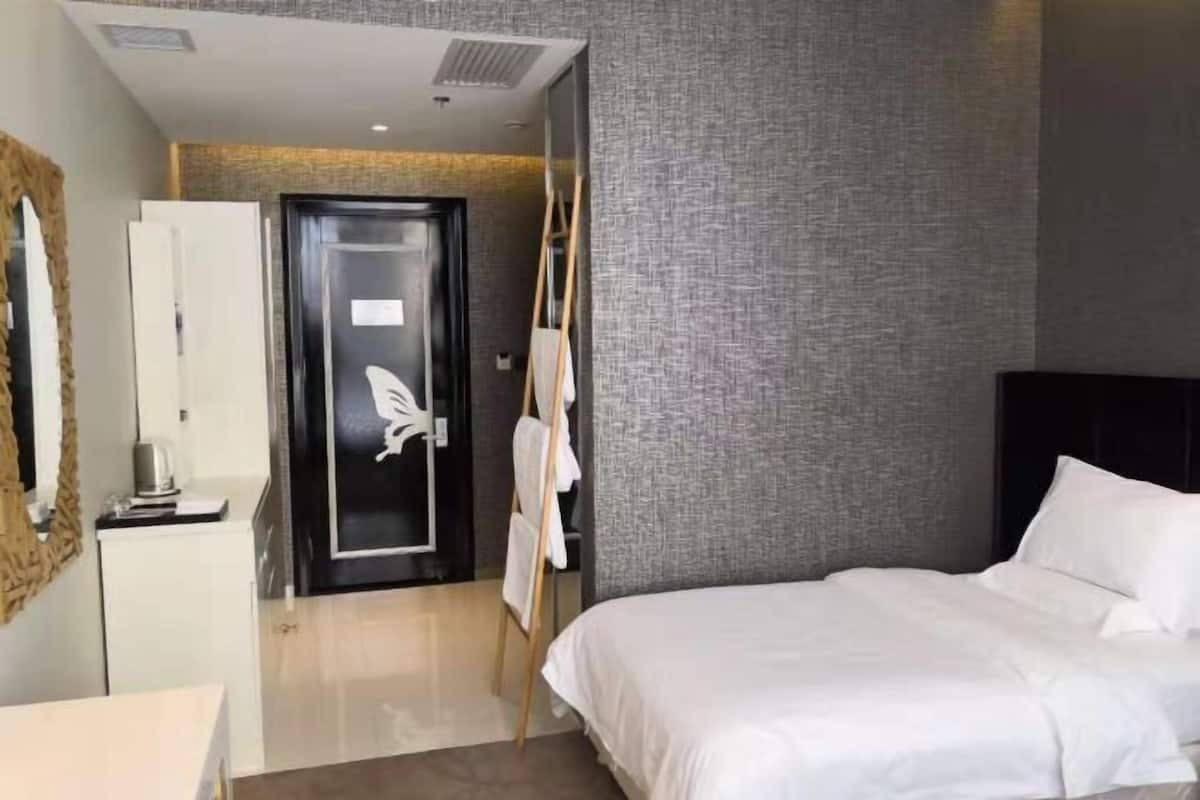 A hotel room with a bed, a desk, and a wardrobe.