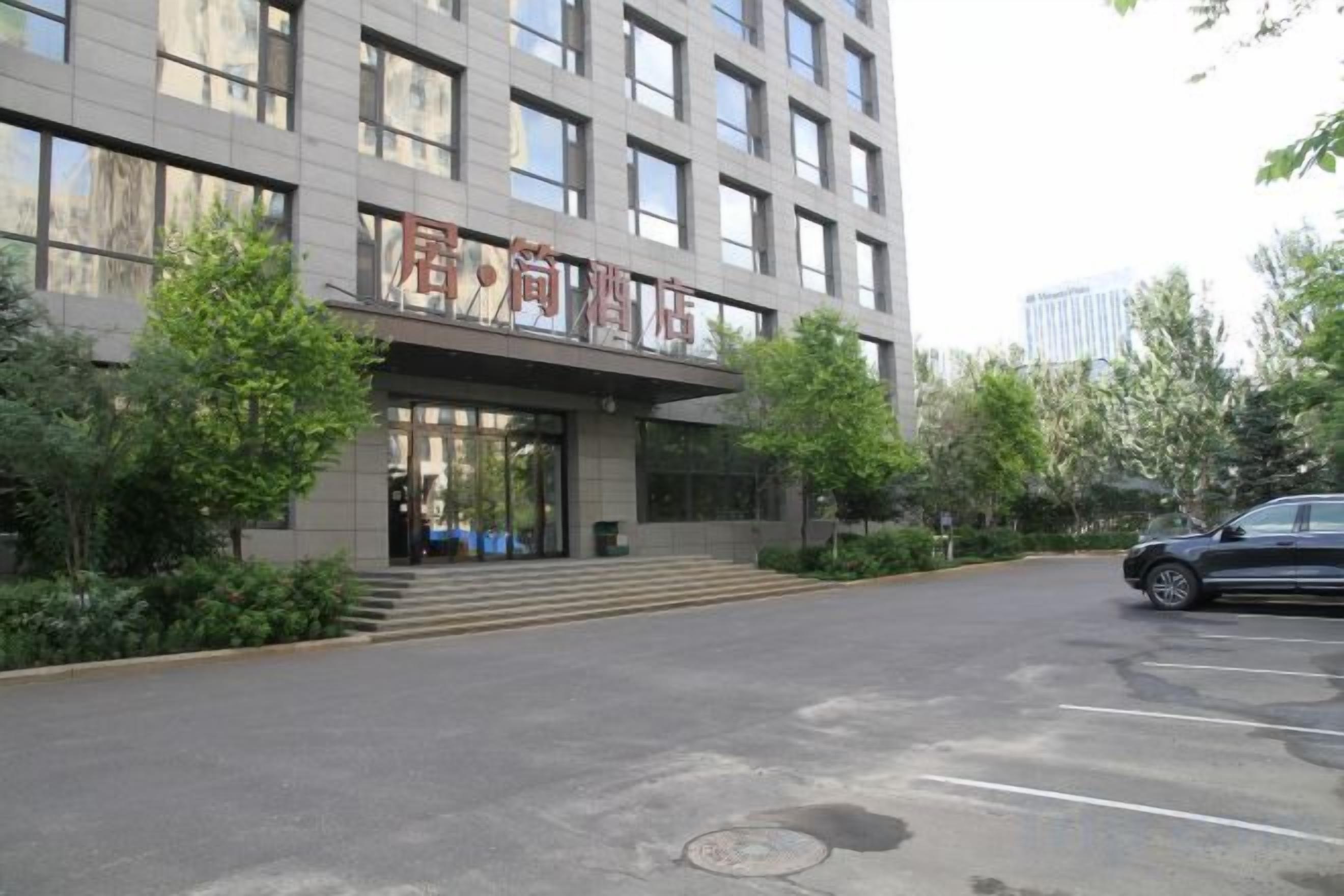 A modern building with a prominent entrance, a parking area, and a car parked in front.