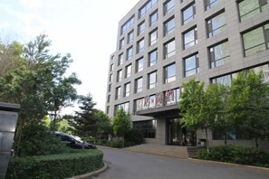 A multi-story building with a modern architectural design, featuring a series of windows and a visible entrance. - Jujian Hotel (Harbin)
