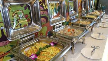 Un bufé con varias estaciones de servicio, cada una con una bandeja metálica y un plato.