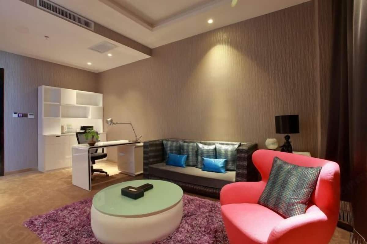 A modern living room with a sofa, a red armchair, a coffee table, and a desk with a computer.