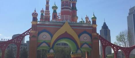 A colorful building with multiple domes and arches, surrounded by modern skyscrapers.