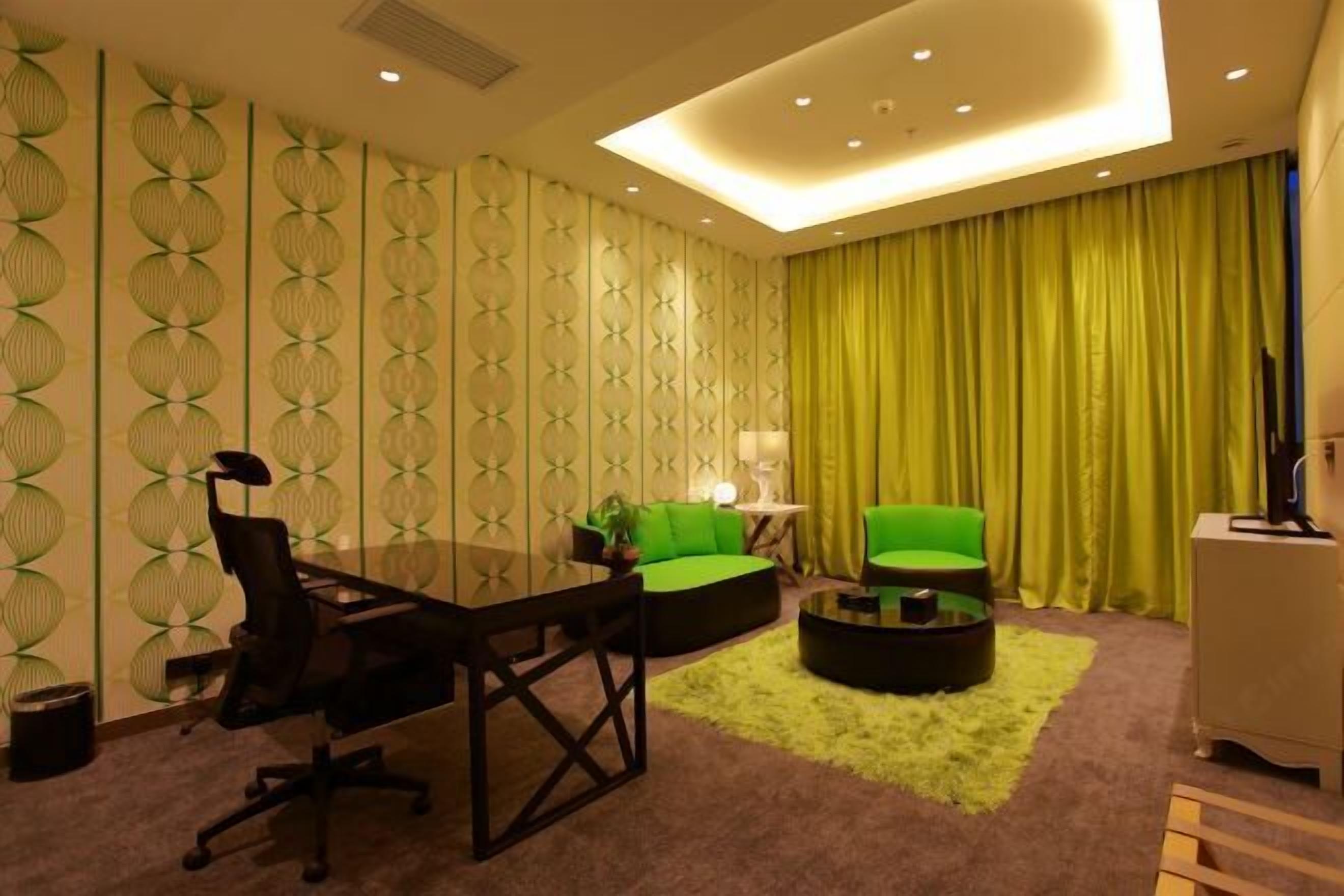 Une pièce moderne avec une table en verre, deux canapés verts, une table basse ronde et un rideau jaune.