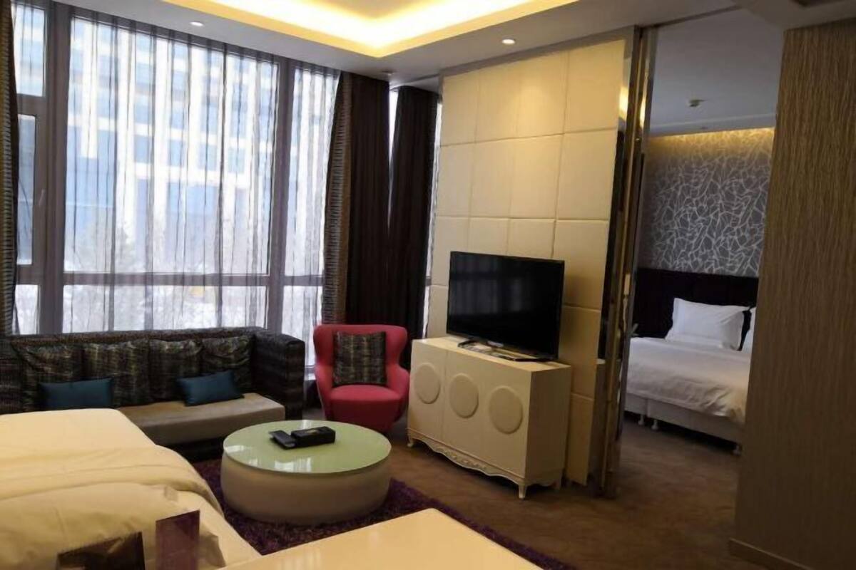A hotel room with a bed, a sofa, a TV, and a small table.