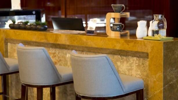 Zona de bar con encimera de mármol, máquina de café y taburetes.