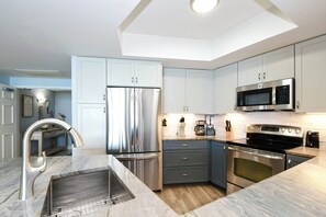 Una cocina moderna con electrodomésticos de acero inoxidable, encimera de mármol y armarios azul claro.
