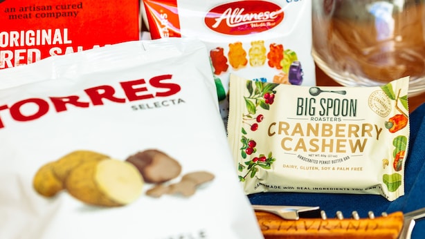 Verschiedene Speisen wie eine Weinflasche, eine Packung Käsesnacks, eine Tüte Putenfleisch und eine Portion geröstete Erdnüsse.