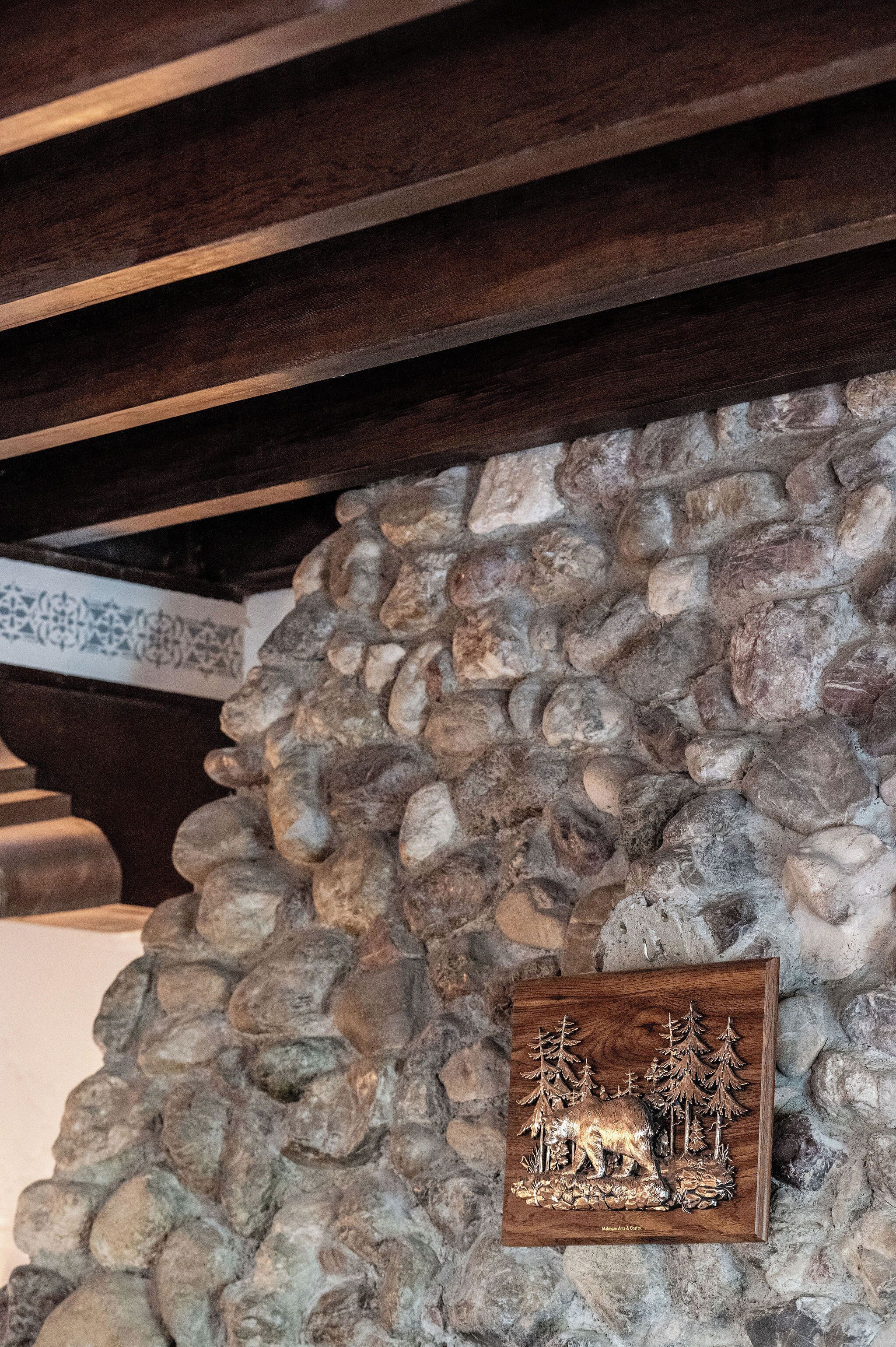 A stone wall with a wooden plaque featuring a bear and trees.
