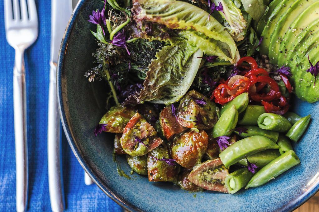 A bowl of salad with various vegetables and greens.