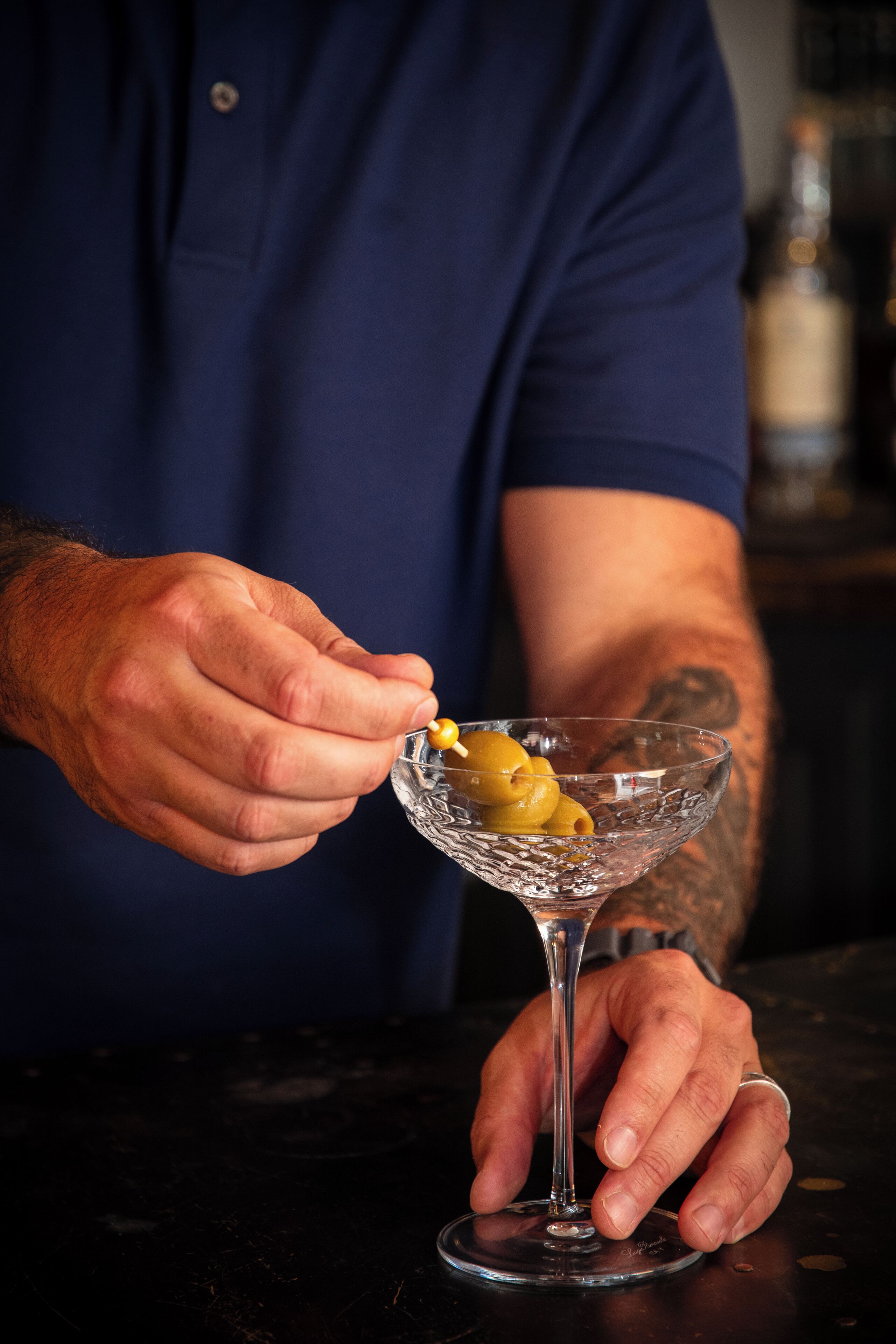 A person holding a martini glass with a lemon twist garnish.