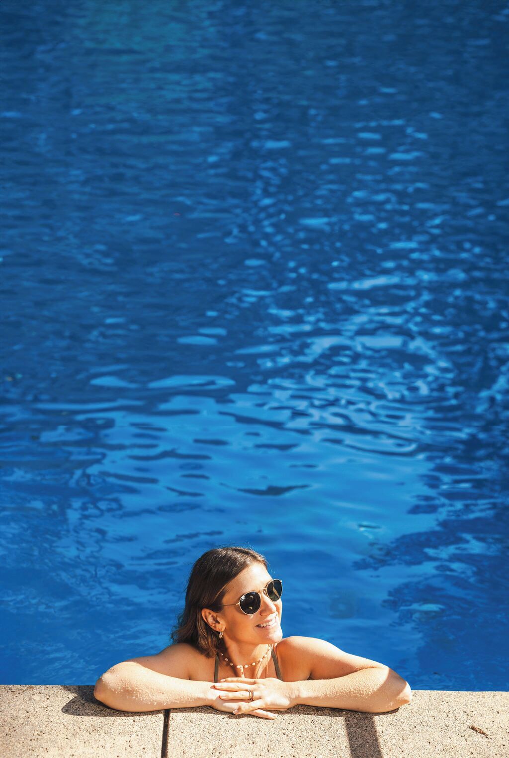 A person relaxing by a pool with clear blue water.