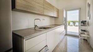 A modern kitchen with a built-in oven, a stainless steel sink, and a view to an outdoor seating area. - Modern 5-BR Villa with Pool, Jacuzzi & Sea View (Ičići)