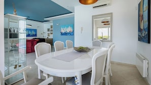 A dining area with a white table, chairs, and a glass cabinet with wine glasses. - Modern 5-BR Villa with Pool, Jacuzzi & Sea View (Ičići)