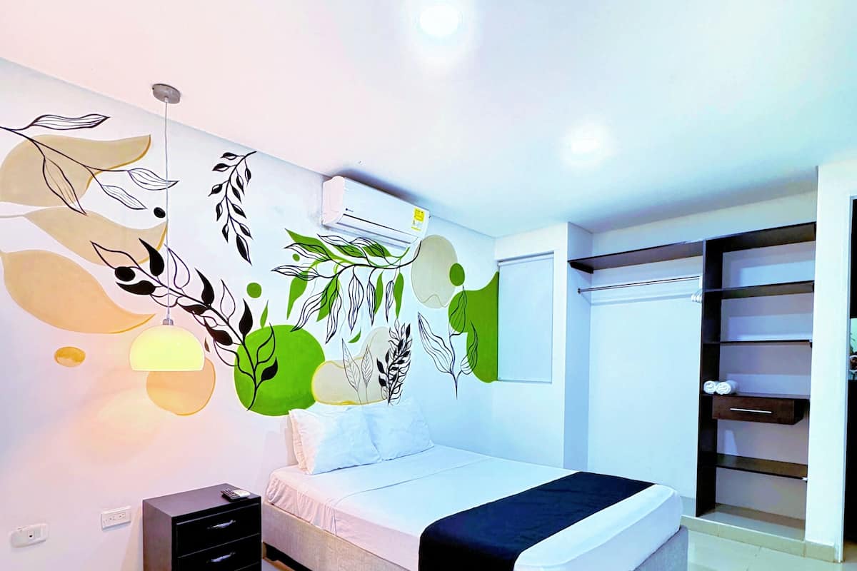 Un dormitorio moderno con cama, mesita de noche, armario y una pared decorada con arte abstracto.