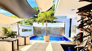 An indoor pool area with a palm tree, lounge chairs, and a stone floor. - Hotel Playa Norte (Cartagena)
