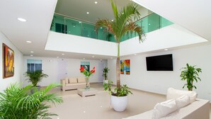 A spacious, modern lobby with a high ceiling, a central palm tree, and a comfortable seating area. - Hotel Playa Norte (Cartagena)