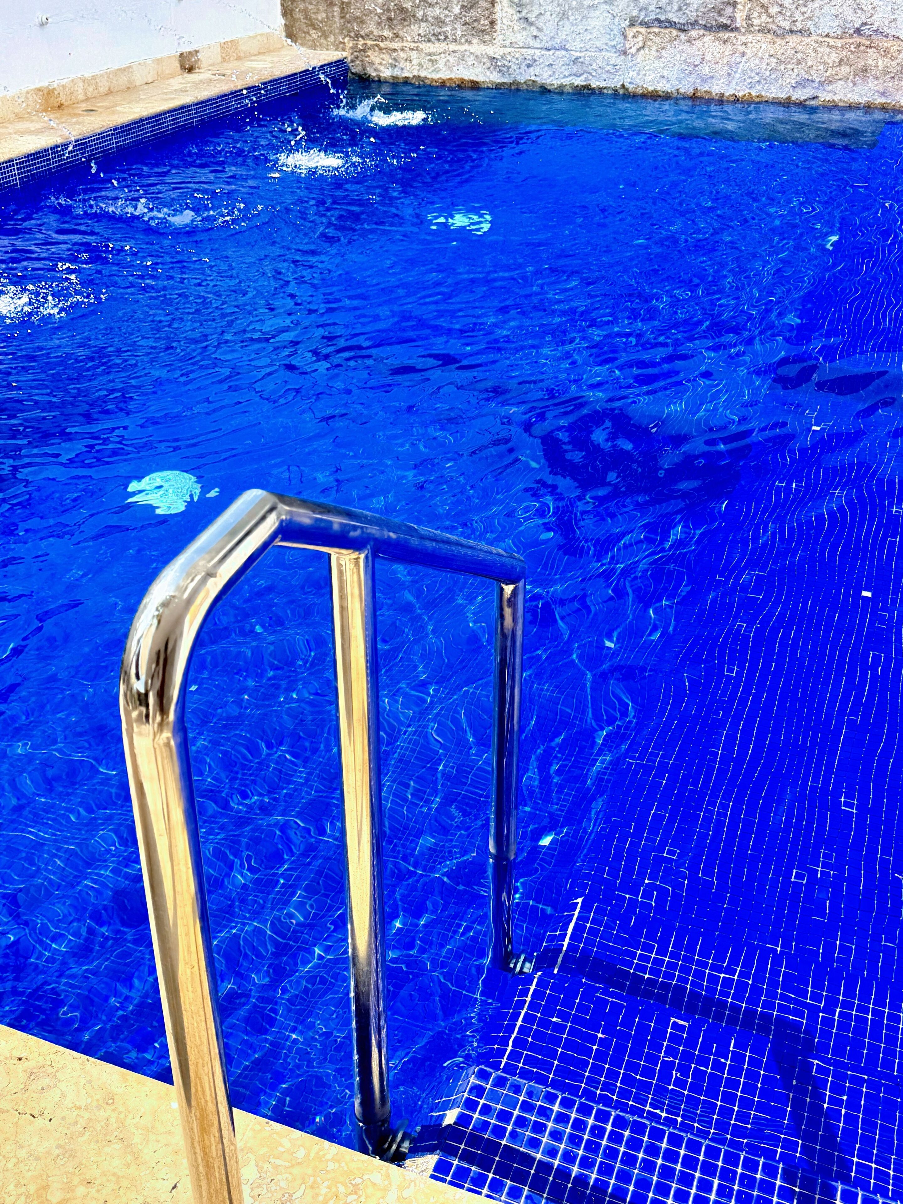 A swimming pool with clear blue water and a metal ladder.
