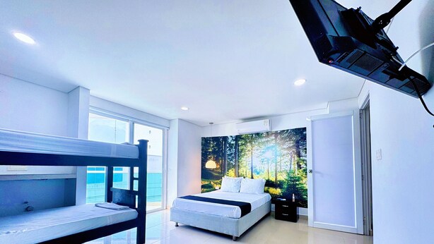 A modern bedroom with bunk beds, a large window, a forest-themed wall mural, and a ceiling-mounted projector. - Hotel Playa Norte (Cartagena)