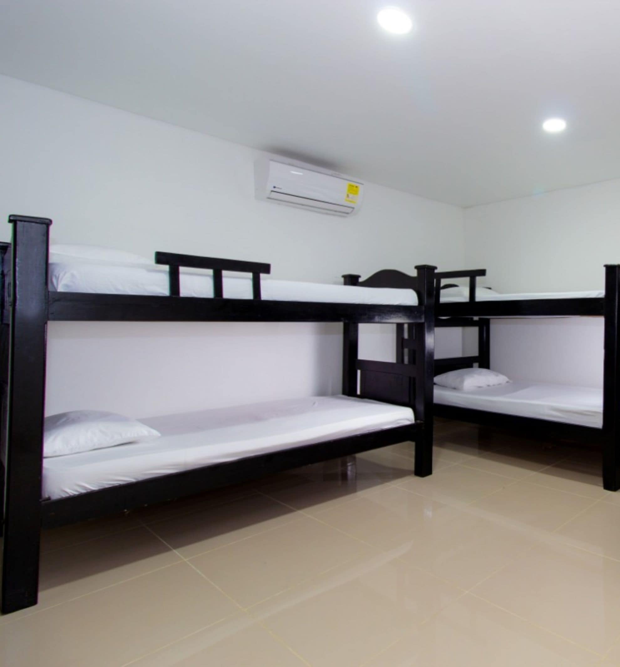A dormitory room with bunk beds, an air conditioning unit, and tiled flooring.