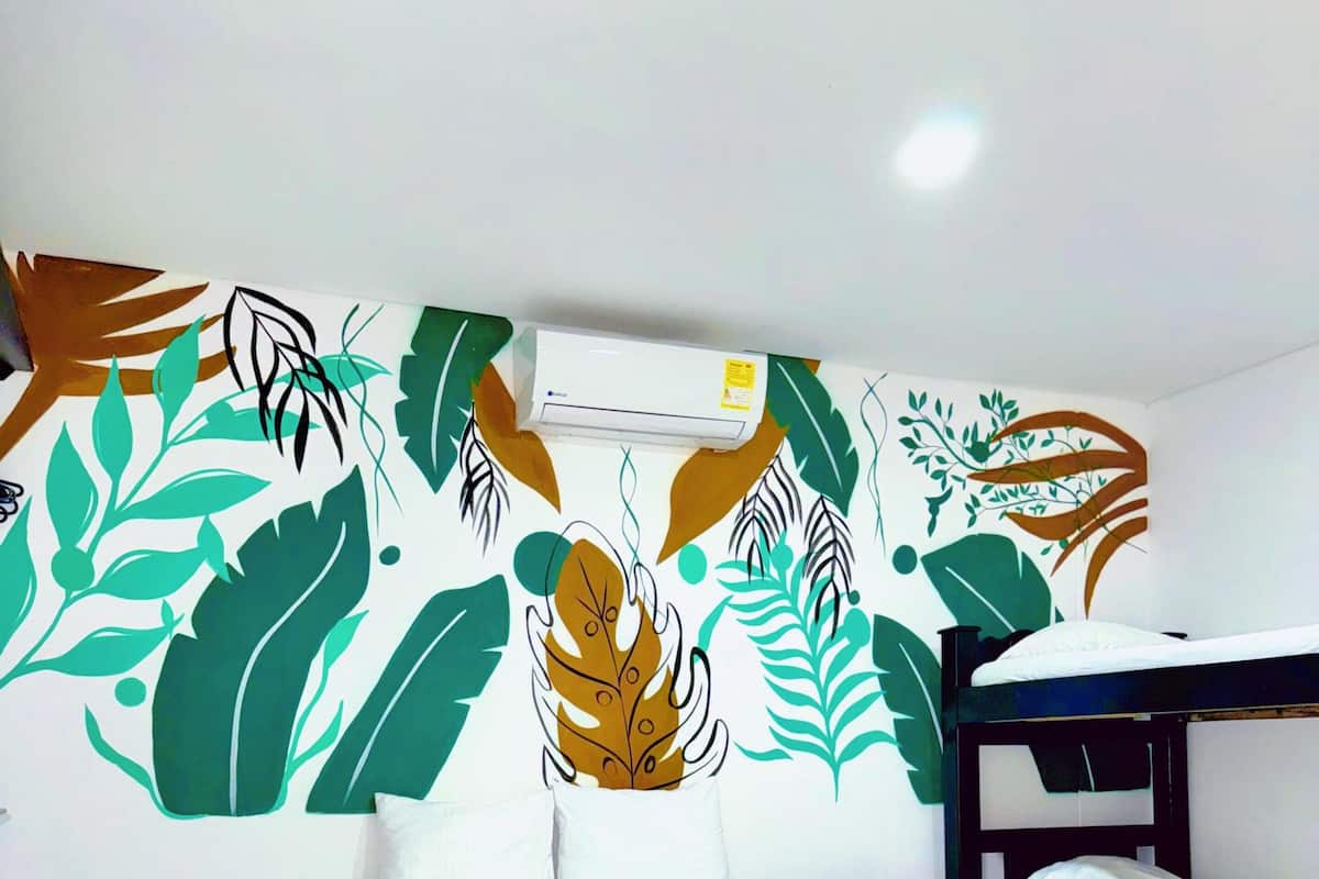 Una habitación con una cama, un escritorio y una pared con un diseño de hojas.
