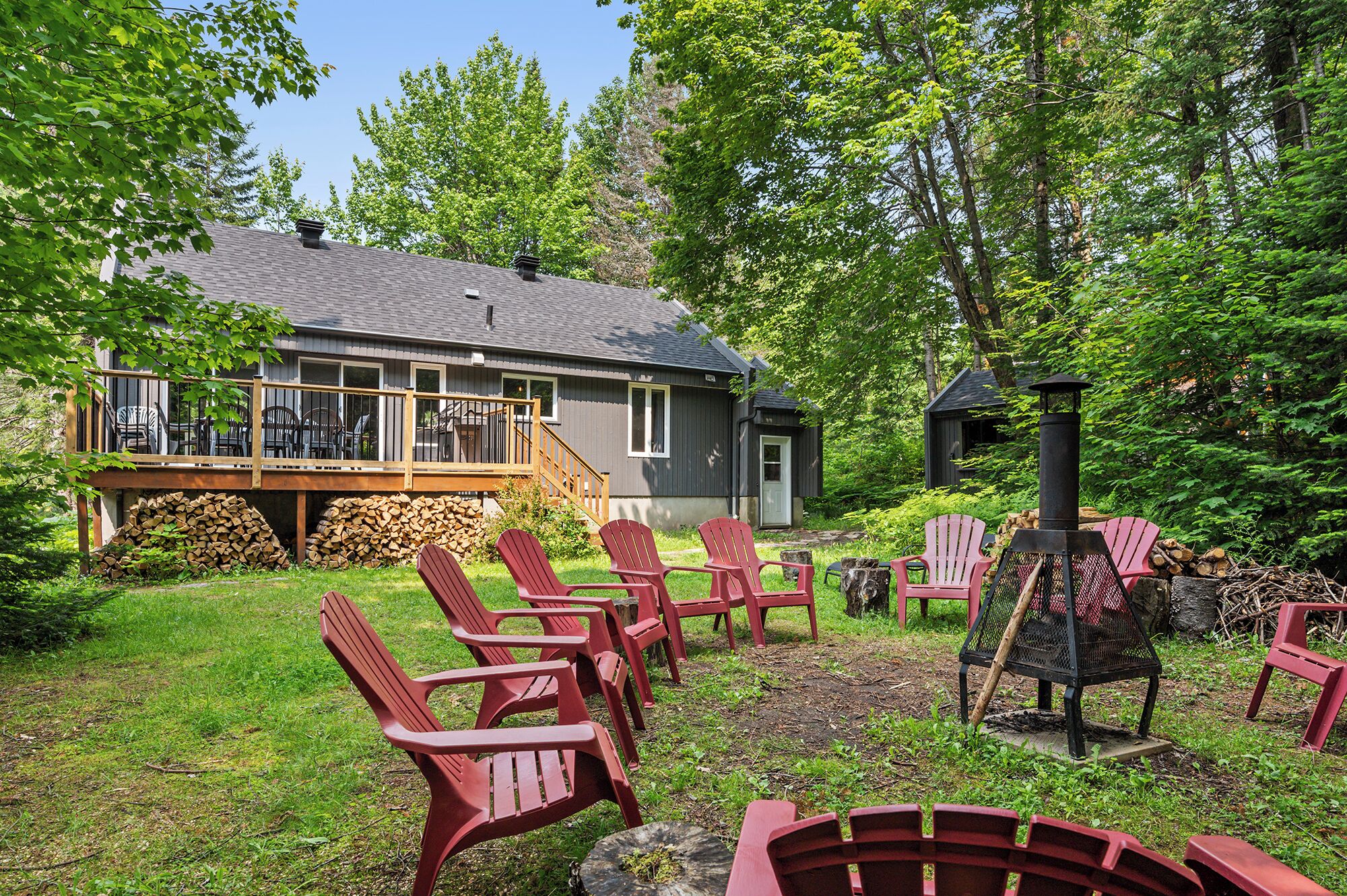 A house with a deck, outdoor seating, and a wood-burning stove.