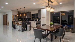 A modern kitchen with a central island, bar stools, and pendant lighting.