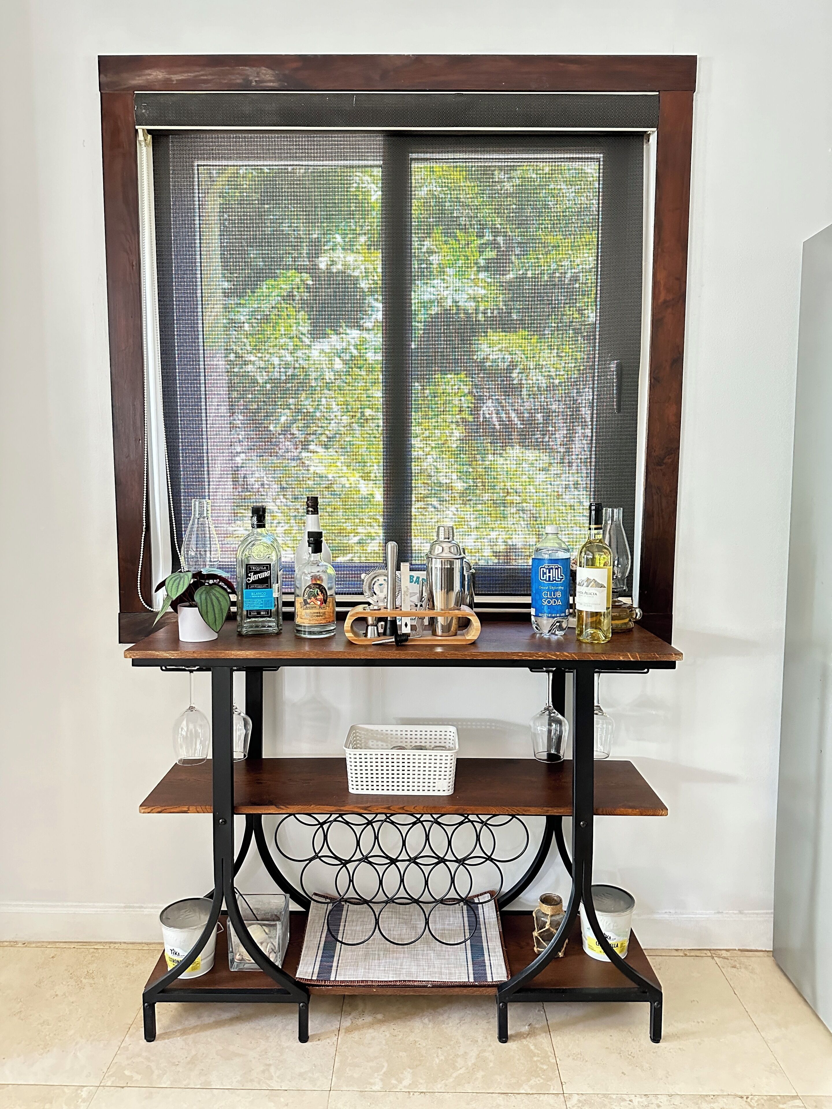 Una mesa de madera con un mosquitero, varias botellas y una cesta.