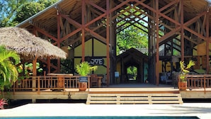 A wooden structure with a thatched roof, a sign reading "JVE", and a pool in the foreground. - Laru Beya Palmetto Bay (Roatan)