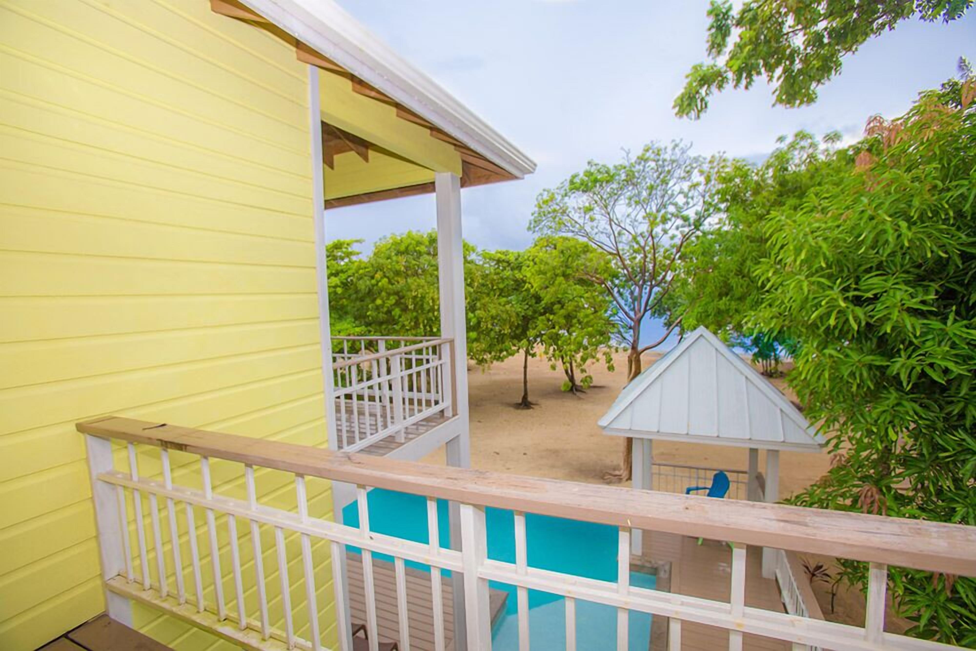 A yellow building with a wooden deck and a small blue pool.